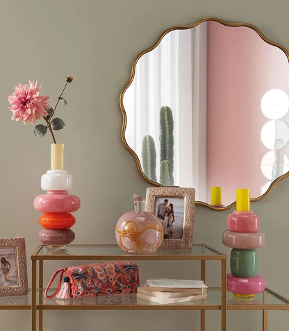 Vaso componibile in vetro rosa e arancione su console dorata con specchio e cornici