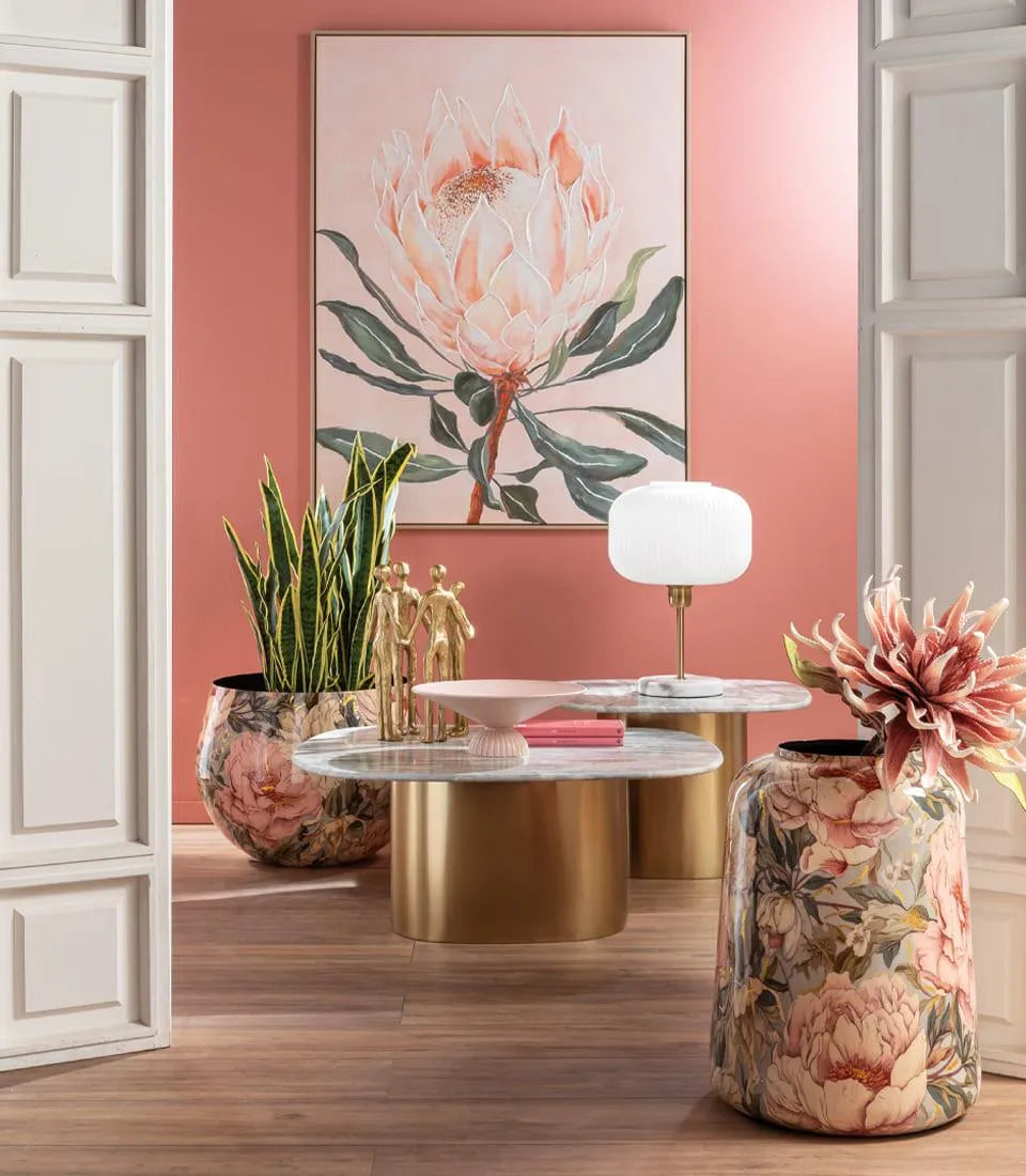 Giara bassa in metallo con decoro floreale rosa in living, accanto ai tavolini